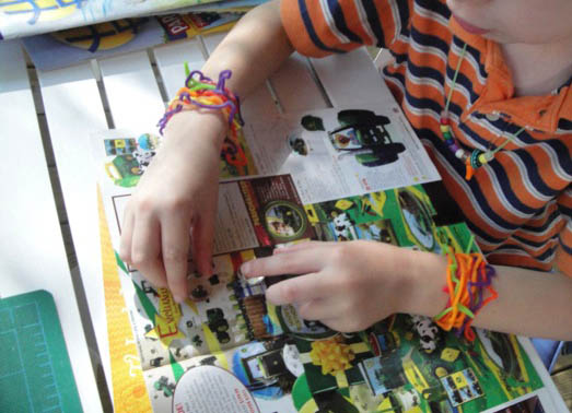 boy laying out glass beads onto magazine pictures