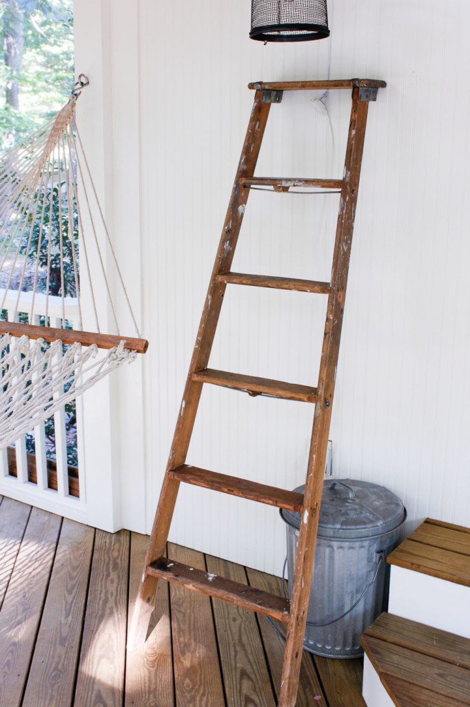 old ladder resting against white porch wall