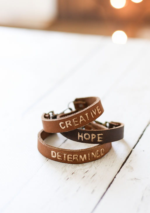 golden tan and dark tan leather bracelets with "creative", "hope", and "determined" stamped on them.
