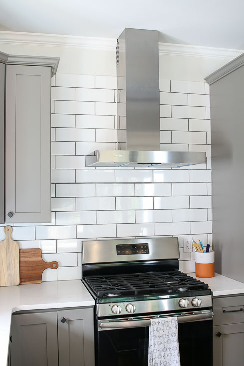 gray shaker cabinets with subway tile backsplash and stainless steel hood from Broan