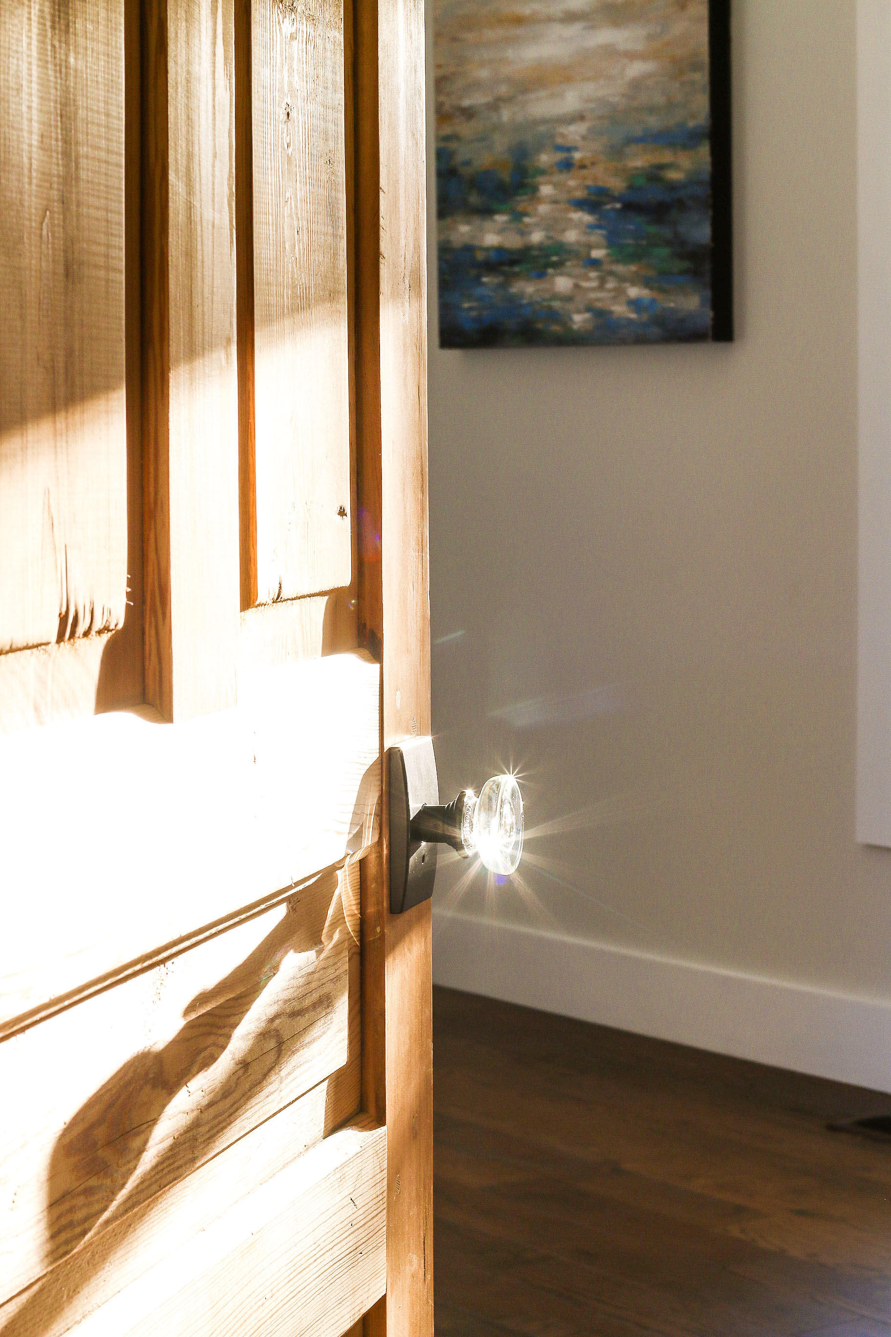 Sun glinting off glass door knob on raw wood door
